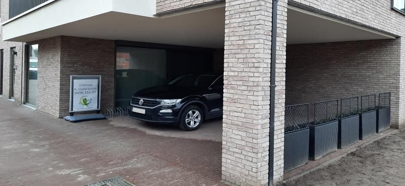 Parking en ingang van de praktijk, met het bord van diëtiste K. Uytersprot